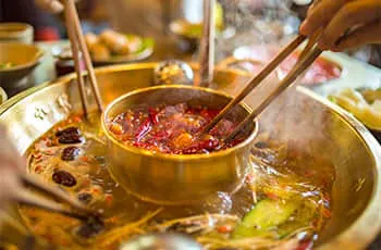 people pick up food from inside soup by chopsticks